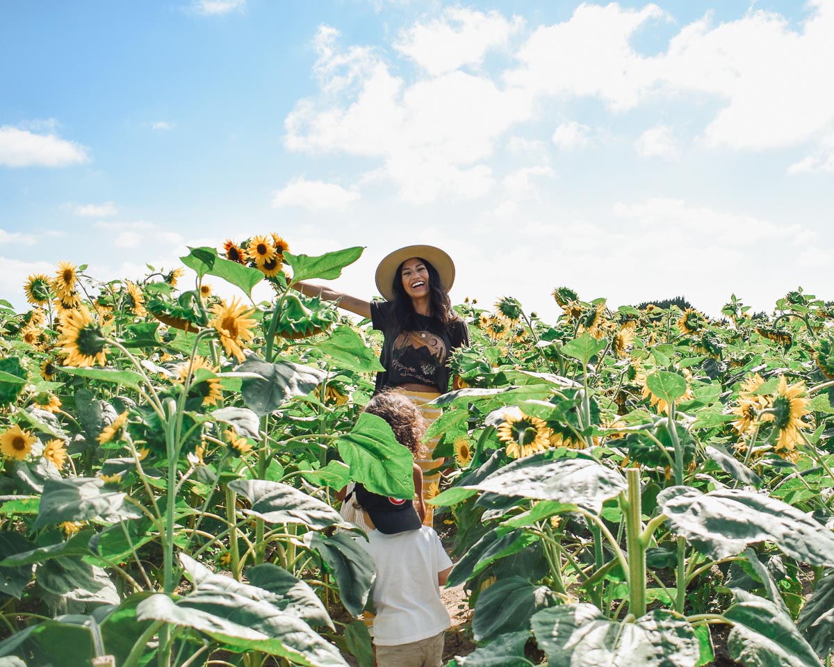 Amanda in the middle of the sunflower field at Emma Lea Farms in Ladner, holding a freshly picked bouquet of flowers.