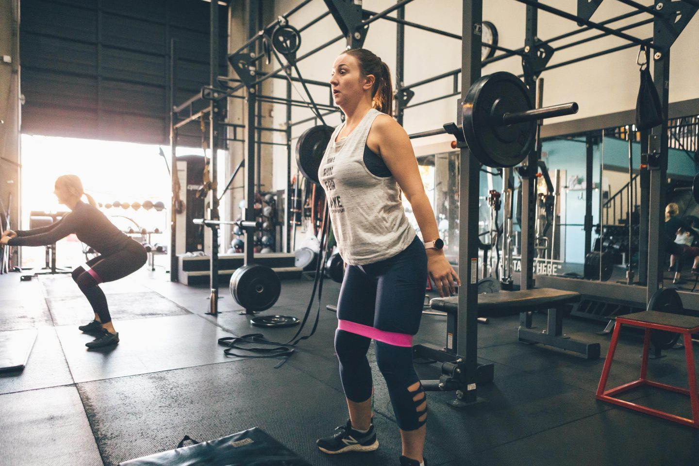 woman in a gym with a resistance band around her thighs exercising